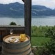 a wine glass and a plate on a barrel with a lake in the background