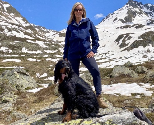 a woman standing next to a dog in front of a snowy mountain